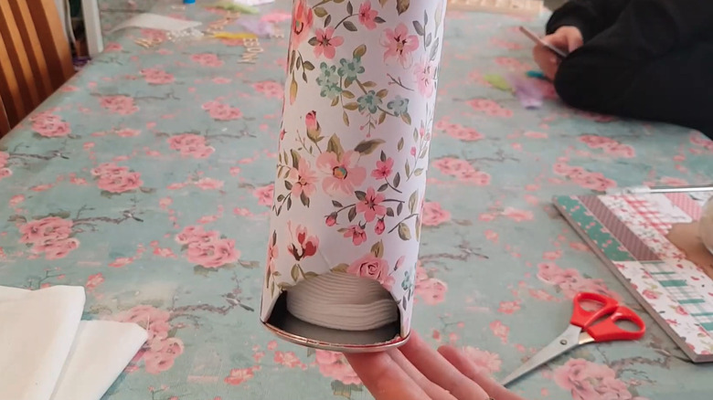 A cotton pad dispenser made of a Pringles can covered with a floral-pattern wallpaper