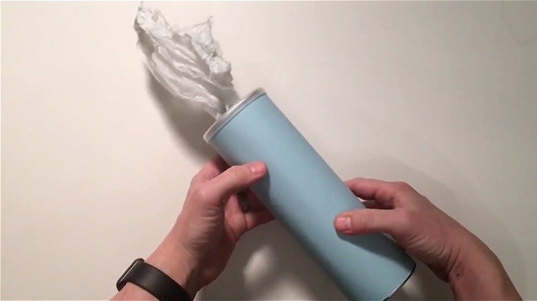 Hands holding a trash bag dispenser made out of a Pringles can