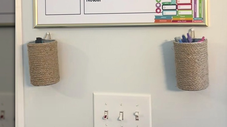 Twine-bound Pringles cans hanging on a wall beneath a whiteboard