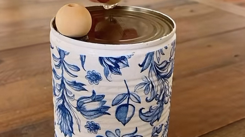 The bottom of the decorative tin as beads are glued down as feet