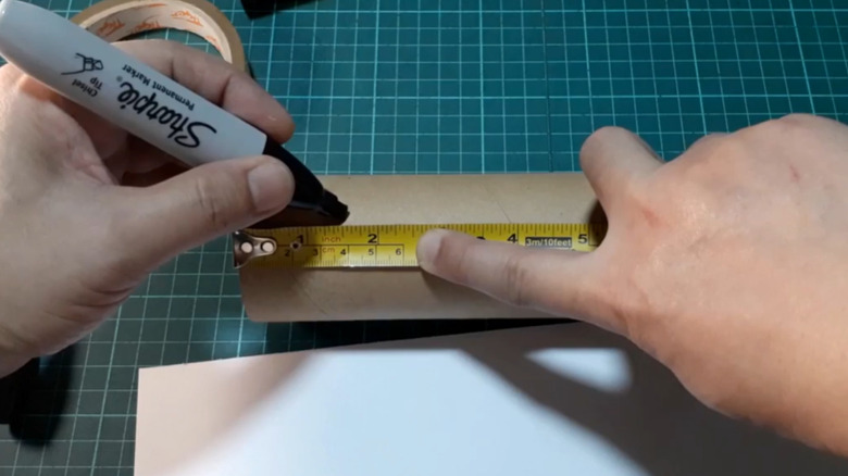 Someone marking a cardboard tube with a sharpie