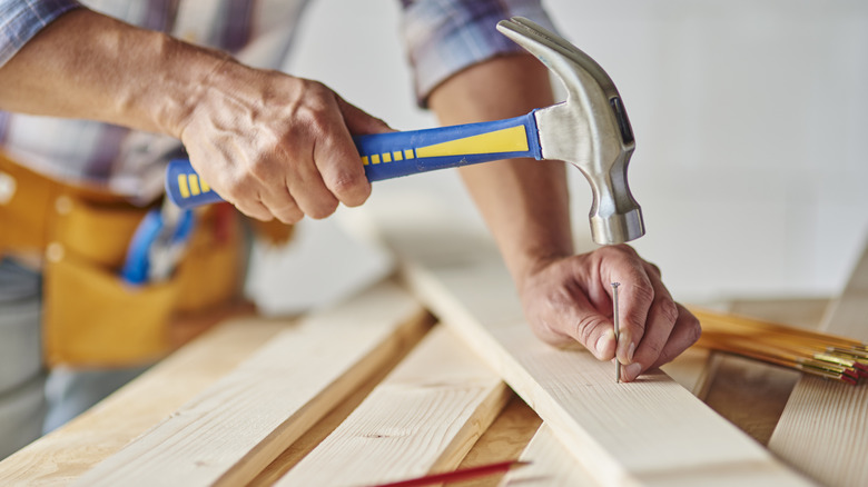 A person hammering a nail into wood