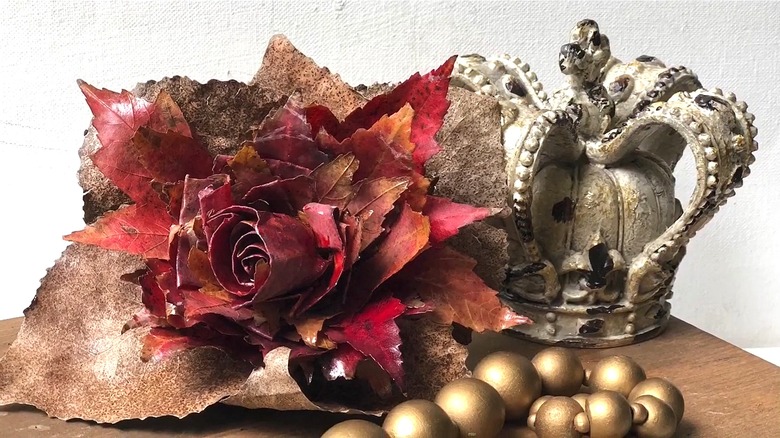 A rose bouquet made out of fallen leaves, paired with a crown and beaded ornaments.
