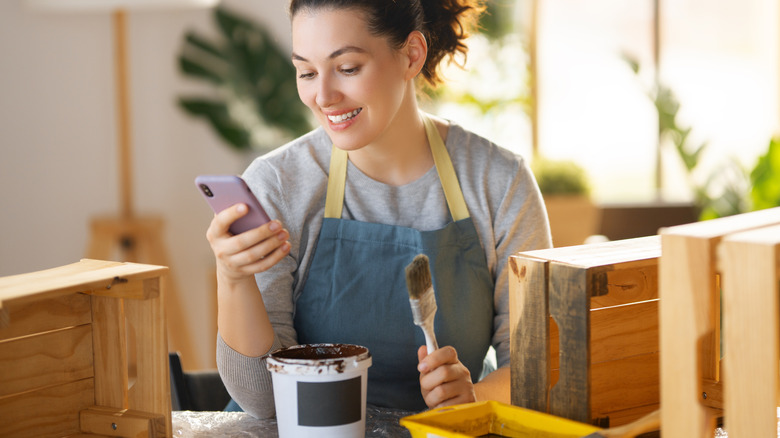 Woman painting a wooden crate