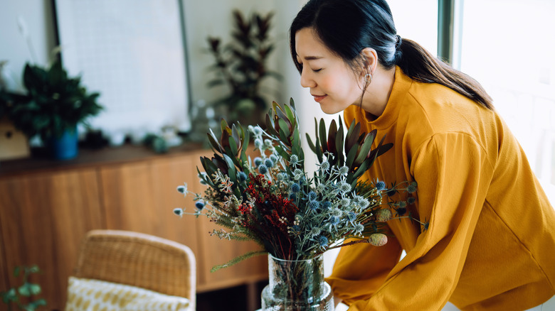 woman with vase of greens in home
