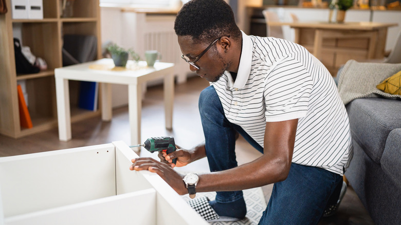 man putting together white bookcase