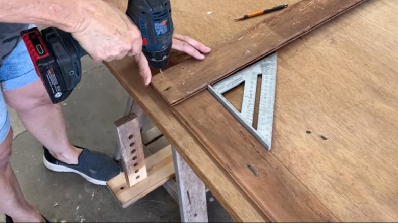 woman screwing in corner of DIY scrap wood frame