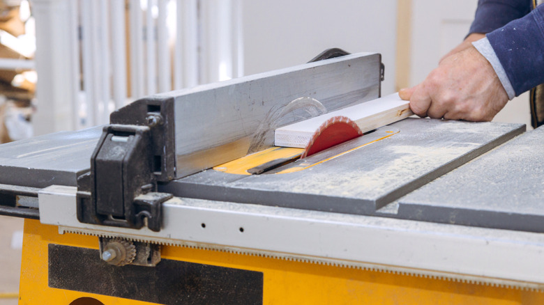 A man using a table saw to cut lumber