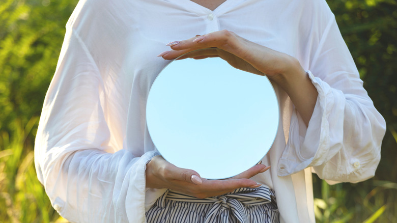Someone holding a small round mirror