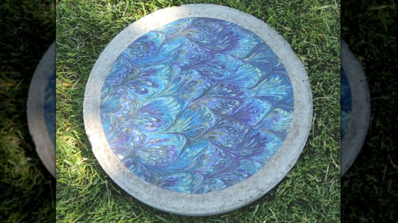A round concrete paver topped with a circle of blue swirly fabric