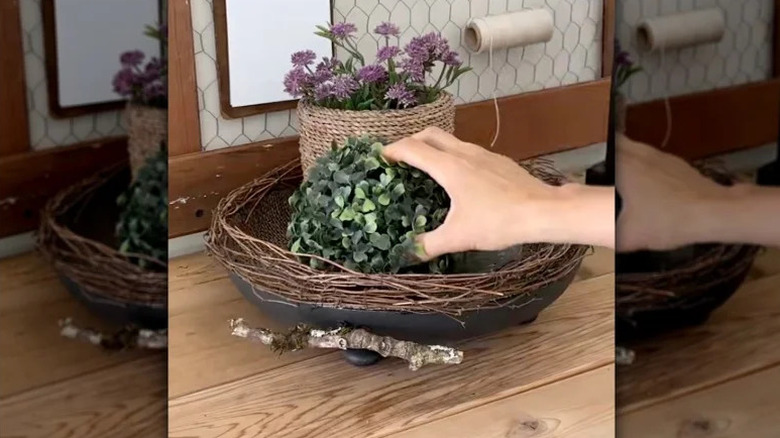 A tiered tray with burlap, twigs, and an old frying pan.