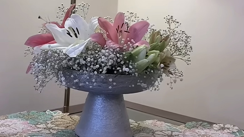 A decorative vase made out of a frying pan base with pretty flowers