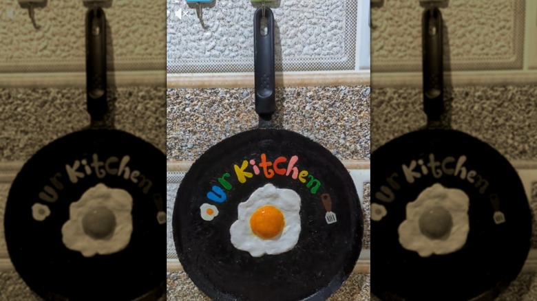 A cast iron featuring a clay fried egg in the middle and the words 'Our kitchen' on top