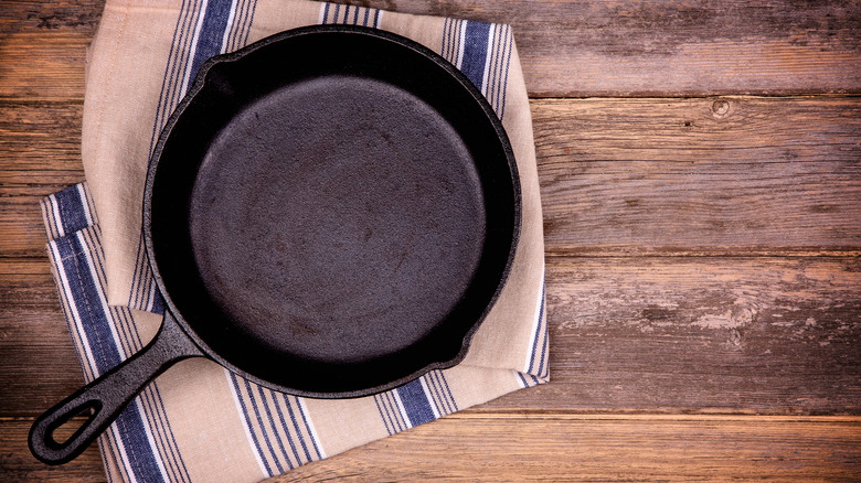 A cast iron skillet sitting on a dish cloth
