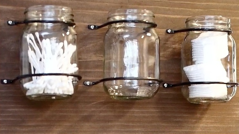 A brown board with glass jars hanging in bathroom