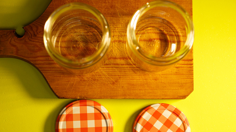 Empty jam jars with lids on cutting board