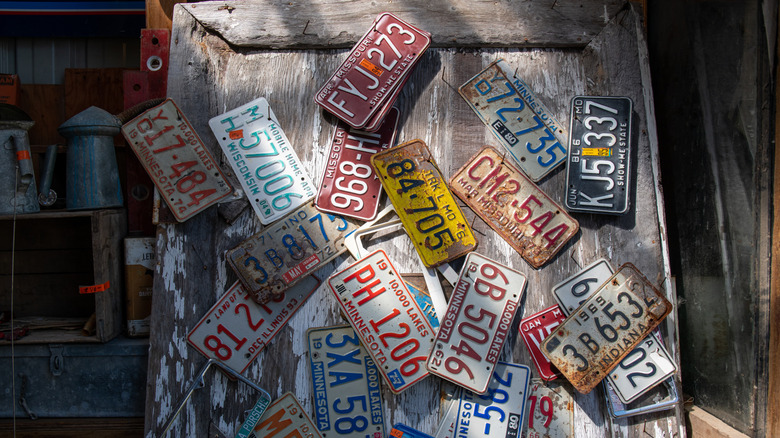 Old license plates scattered one a rough wood surface.