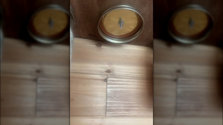 Close-up of mason jar lid attached to cabinet bottom