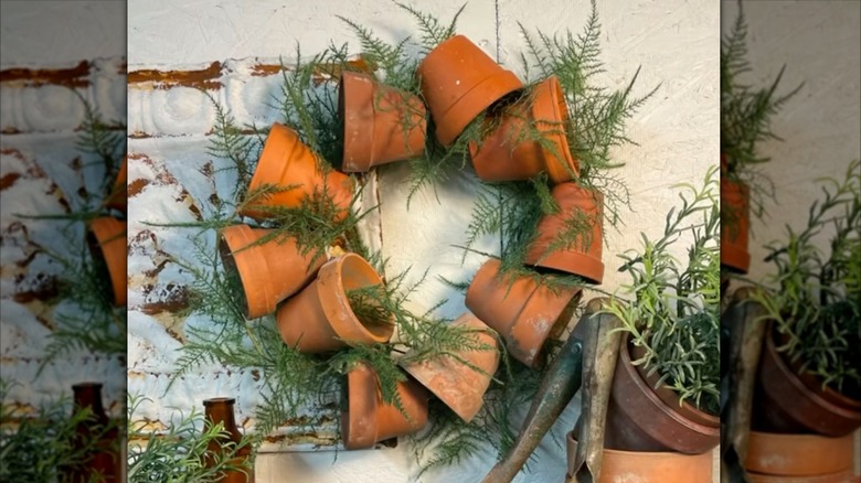 Wreath made of old mini nursery pots and faux greenery hanging in garden shed.