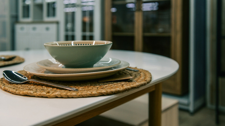 A round, natural placemat underneath dishes on a dining table
