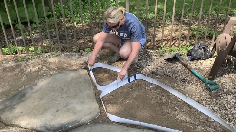 A person in a garden laying out concrete molds made from vinyl blind strips