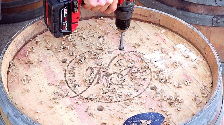 Close-up of a person drilling holes into the bottom of a wine barrel planter