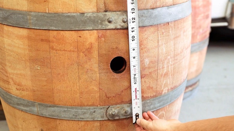 Close-up of a person taking a measuring of a wooden wine barrel
