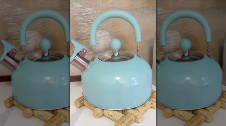 A blue teapot on a cork trivet