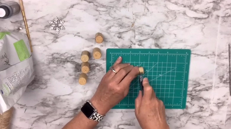Person cutting wine corks on a green cutting mat