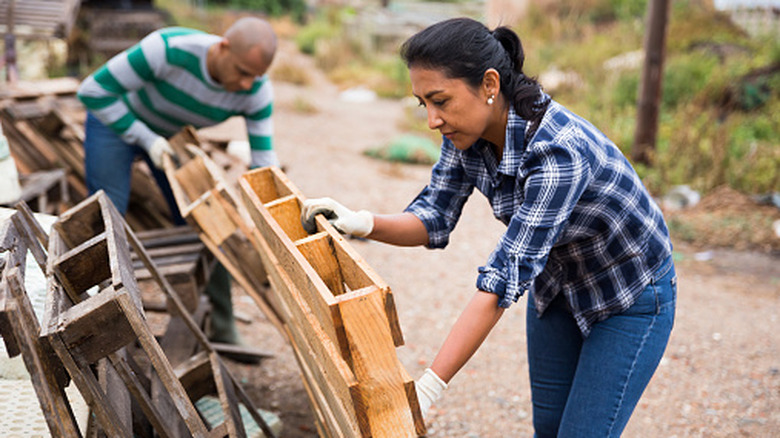 two people examine an assortment of wood pallets