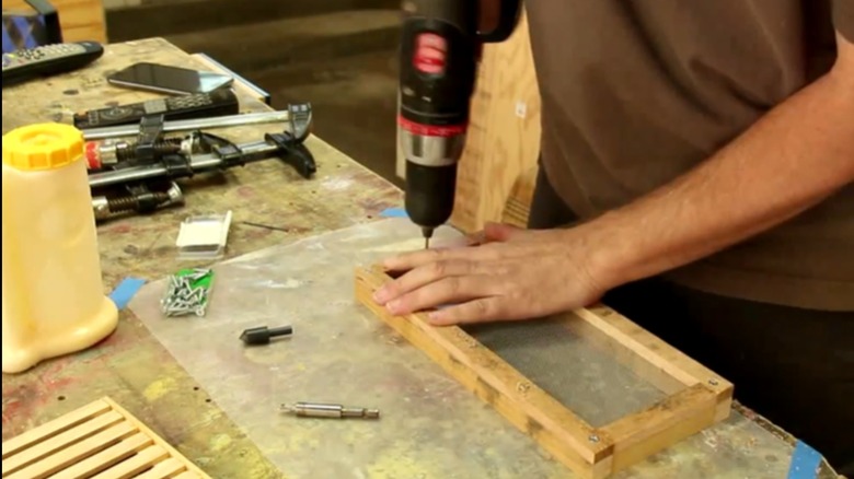 Demonstrator screwing together two frames with mesh screening in between