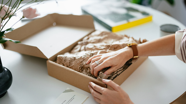 Someone unwrapping a package filled with packing paper