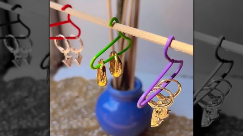 Mini hangers for jewelry made from colorful paper clips hanging from wooden dowel