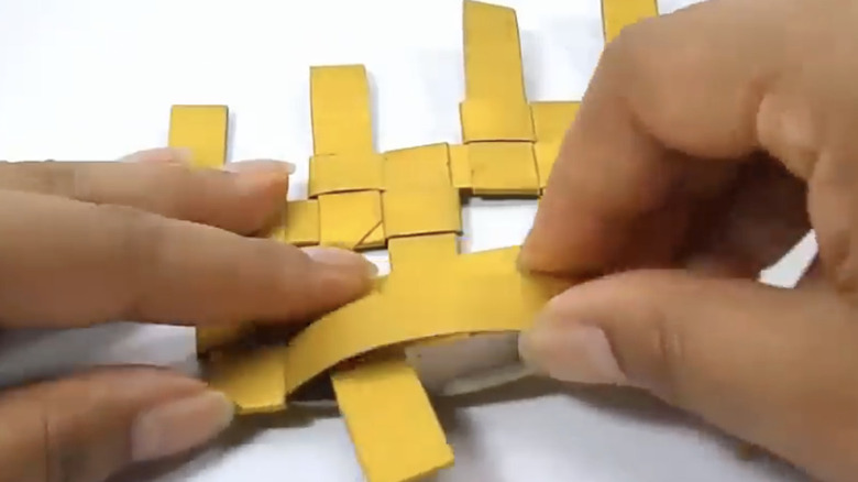 Folding cardboard strips in a basket weave.