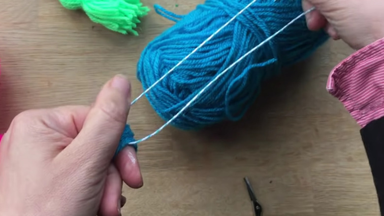 Hands making a decorative tassel out of yarn
