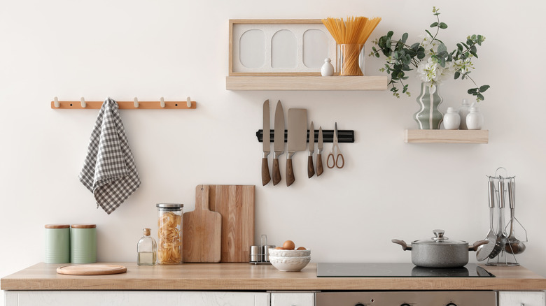 A kitchen countertop with cutting boards and canisters on it and several floating shelves above it