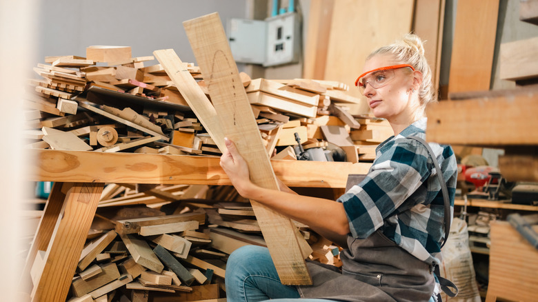 A woman inspecting pieces of scrap wood