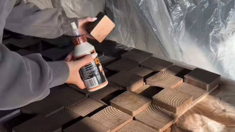 Person gluing scrap wood slices and attaching to plywood