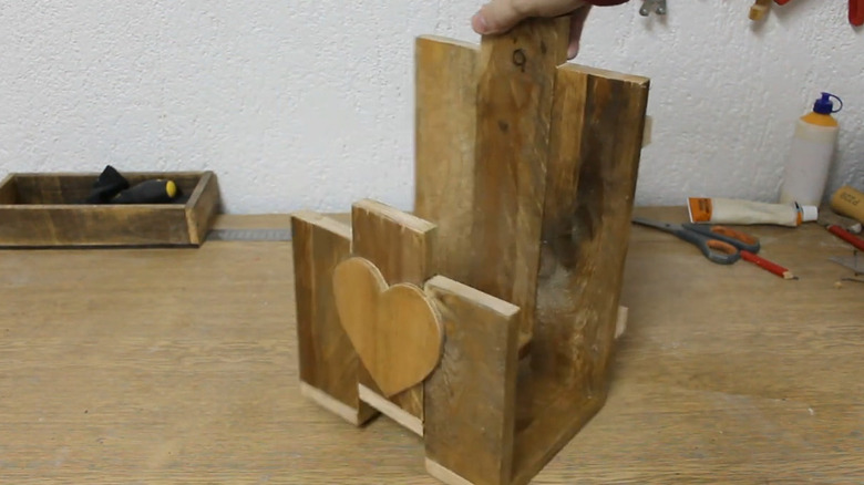 A hose hanger made from pallet wood with a decorative heart-shaped front decoration.