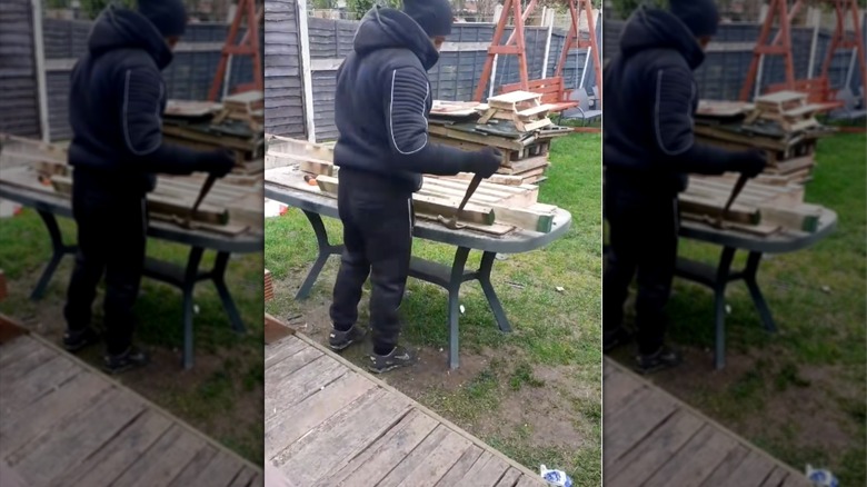 Person using a hammer to pry nails from a piece of wood