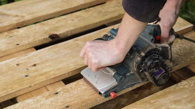 Person sanding a wood pallet