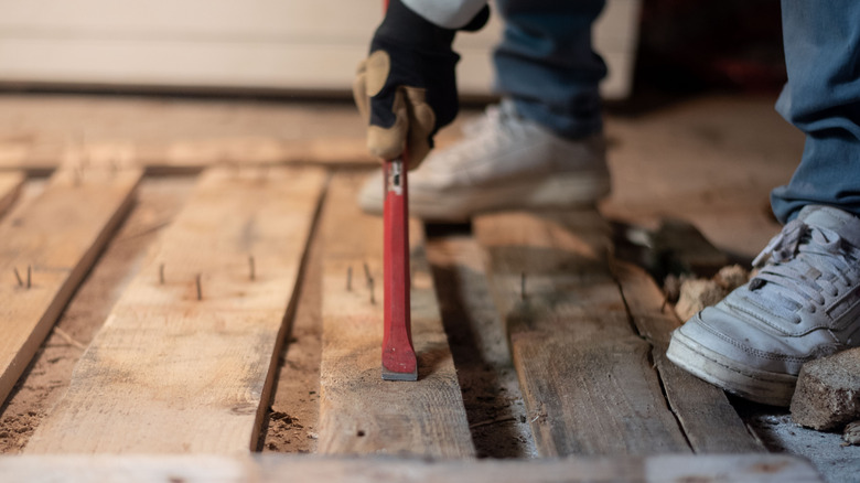 Person pulling old nails from a wood pallet