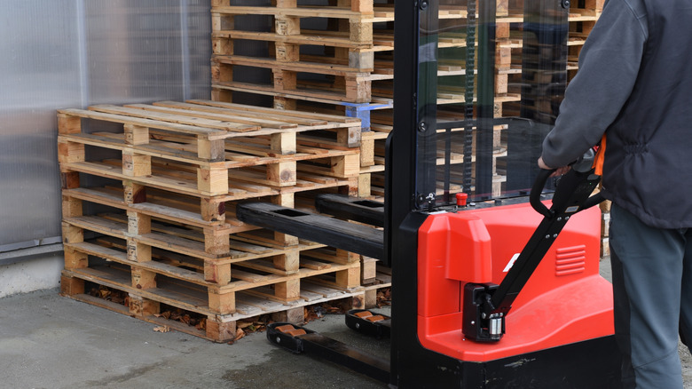 Forklift picking up a stack of wooden pallets