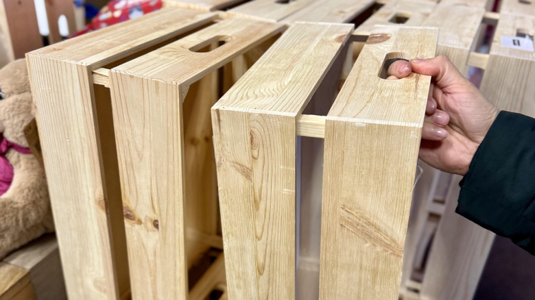 Person grabbing a wooden crate