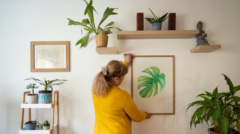 A woman hanging a print on a gallery wall.