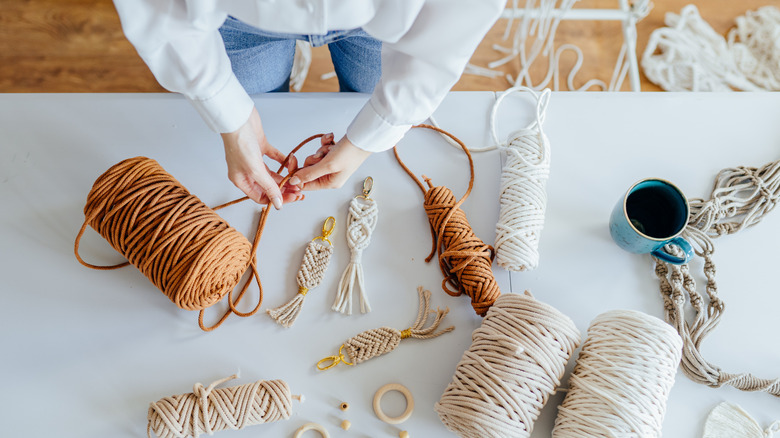 A person weaving macramé at a white table