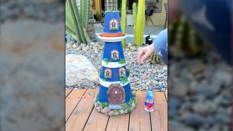 A blue and white decorated lighthouse made from a stack of planters