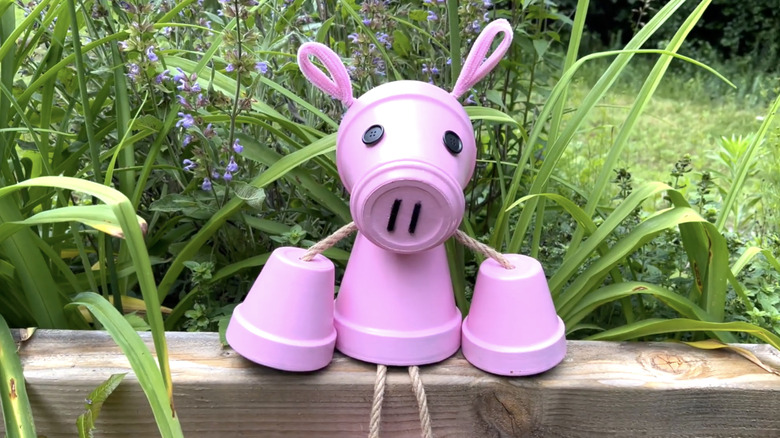 A pink pig made from terracotta pots, rope, and craft supplies.