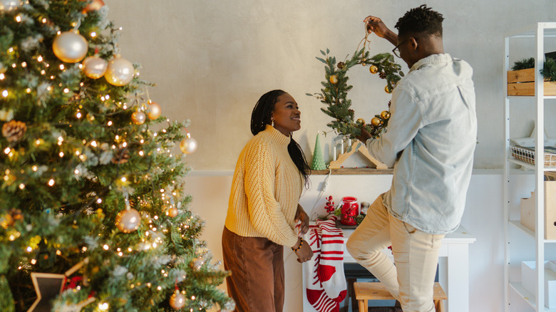 A couple decorates their living room for Christmas