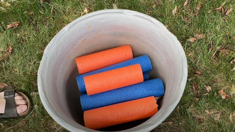 Orange and blue pool noodles cut up and set at the bottom of the planter.
